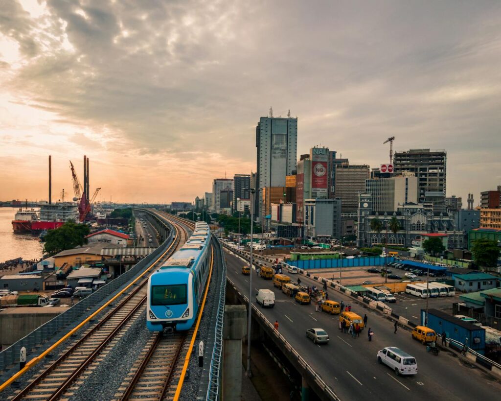 pexels-photo-27792546 Aerial view of a train passing through Lagos, highlighting the city's urban skyline and bustling transport systems.