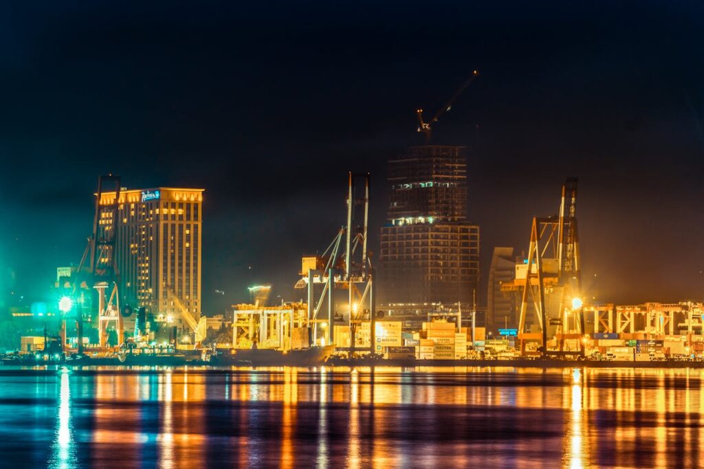 pexels-photo-3037269 A vibrant city harbor at night with reflecting lights and industrial cranes.